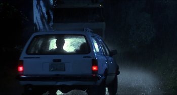 Movie still from “Castle Freak” (1995), directed by Stuart Gordon – Two people sitting in the back of a car in the rain; Wide shot, Low angle
