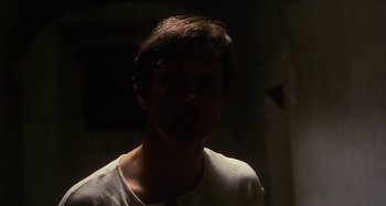 Movie still from “Castle Freak” (1995), directed by Stuart Gordon – A man in a white shirt is in a dark room; Close Up shot, Low angle