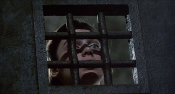 Movie still from “Castle Freak” (1995), directed by Stuart Gordon – A woman looking through a jail cell window; Close Up shot, Low angle