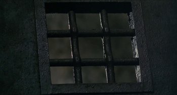 Movie still from “Castle Freak” (1995), directed by Stuart Gordon – A view through a window of a metal fence; Extreme Close Up shot, Overhead angle