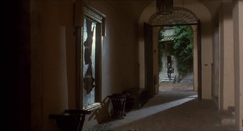 Movie still from “Castle Freak” (1995), directed by Stuart Gordon – A hallway with a broken window and a person walking by; Extreme Wide shot, Over the shoulder angle
