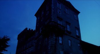 Movie still from “Castle Freak” (1995), directed by Stuart Gordon – A building that has a balcony on top of it at night time; Extreme Wide shot, Low angle