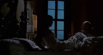 Movie still from “Castle Freak” (1995), directed by Stuart Gordon – A woman sitting on a bed looking out a window; Wide shot, Low angle