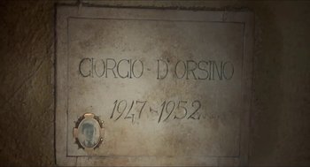 Movie still from “Castle Freak” (1995), directed by Stuart Gordon – A stone wall with a picture of a person on it; Extreme Close Up shot, High angle