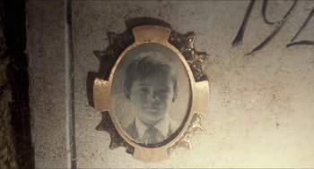 Movie still from “Castle Freak” (1995), directed by Stuart Gordon – An old photo of a young man in a frame; Extreme Close Up shot, Overhead angle