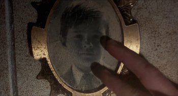 Movie still from “Castle Freak” (1995), directed by Stuart Gordon – A hand is touching a picture of a man in a mirror; Extreme Close Up shot, Overhead angle
