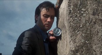 Movie still from “Castle Freak” (1995), directed by Stuart Gordon – A man in a suit and tie holding a can of soda; Close Up shot, Low angle