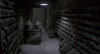 Movie still from “Castle Freak” (1995), directed by Stuart Gordon – A room filled with lots of bottles and baskets; Extreme Wide shot, High angle