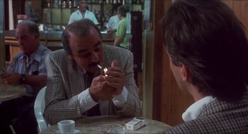 Movie still from “Castle Freak” (1995), directed by Stuart Gordon – A man smoking a cigarette in front of another man in a suit; Medium shot, Over the shoulder angle
