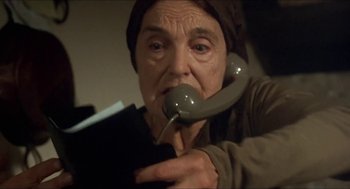 Movie still from “Castle Freak” (1995), directed by Stuart Gordon – An older woman holding a phone up to her mouth; Close Up shot, Low angle