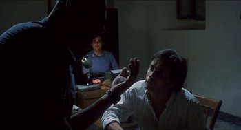 Movie still from “Castle Freak” (1995), directed by Stuart Gordon – A man in white shirt holding a knife in front of a mirror; Medium shot, Over the shoulder angle