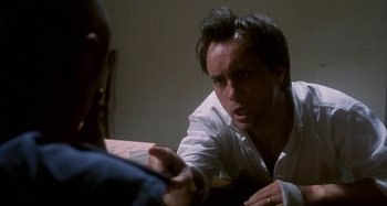 Movie still from “Castle Freak” (1995), directed by Stuart Gordon – A man in white shirt talking to another man in a room; Close Up shot, Over the shoulder angle
