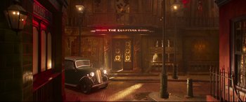 Movie still from “Cats” (2019), directed by Tom Hooper – An old car parked in front of a building; Extreme Wide shot, Low angle