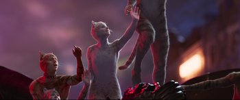 Movie still from “Cats” (2019), directed by Tom Hooper – A woman in a cat costume standing next to a man; Medium shot, Overhead angle