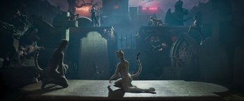 Movie still from “Cats” (2019), directed by Tom Hooper – A cat sitting on the ground in front of a graveyard; Wide shot, High angle