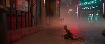 Movie still from “Cats” (2019), directed by Tom Hooper – A person sitting on the ground on a city street; Wide shot, High angle