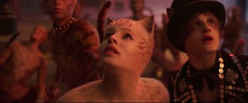 Movie still from “Cats” (2019), directed by Tom Hooper – A woman with a cat's face and a crowd of people behind her; Close Up shot, Low angle