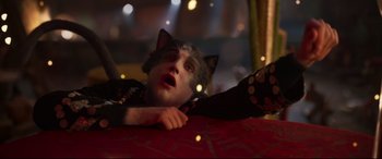 Movie still from “Cats” (2019), directed by Tom Hooper – A person laying on a bed next to lights; Close Up shot, High angle