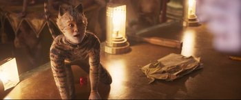 Movie still from “Cats” (2019), directed by Tom Hooper – A cat that is sitting on the ground; Close Up shot, High angle