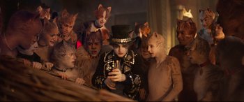 Movie still from “Cats” (2019), directed by Tom Hooper – A group of people dressed as cats looking at a cell phone; Medium shot, High angle