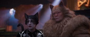 Movie still from “Cats” (2019), directed by Tom Hooper – Two people dressed up as cats in front of lights; Medium shot, Low angle