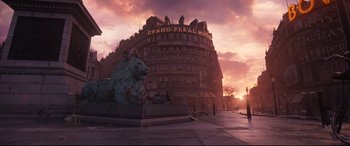 Movie still from “Cats” (2019), directed by Tom Hooper – A statue of a lion in front of a large building; Extreme Wide shot, Low angle