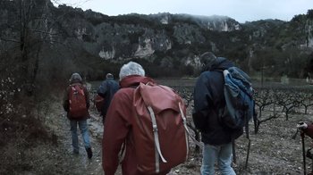 Movie still from “Cave of Forgotten Dreams” (2010), directed by Werner Herzog – A group of people with backpacks walking across a field; Wide shot, Low angle