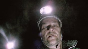 Movie still from “Cave of Forgotten Dreams” (2010), directed by Werner Herzog – A person wearing a helmet with a light on it; Extreme Close Up shot, Overhead angle