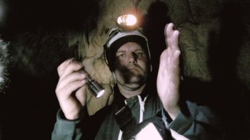 Movie still from “Cave of Forgotten Dreams” (2010), directed by Werner Herzog – A man holding a cell phone in a cave; Close Up shot, Low angle