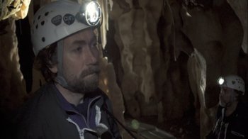 Movie still from “Cave of Forgotten Dreams” (2010), directed by Werner Herzog – A man wearing a hard hat with a light on his head; Close Up shot, Over the shoulder angle