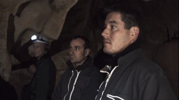 Movie still from “Cave of Forgotten Dreams” (2010), directed by Werner Herzog – A group of men standing next to each other in a cave; Medium shot, High angle