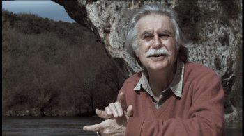 Movie still from “Cave of Forgotten Dreams” (2010), directed by Werner Herzog – An older man with a beard and a mustache; Medium shot, Low angle