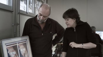Movie still from “Cave of Forgotten Dreams” (2010), directed by Werner Herzog – A man and a woman looking at a picture; Medium shot, High angle