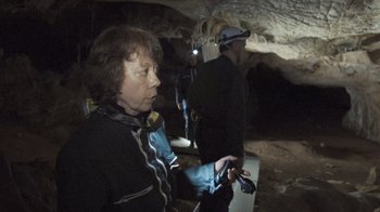 Movie still from “Cave of Forgotten Dreams” (2010), directed by Werner Herzog – A group of people standing inside of a cave; Medium shot, Over the shoulder angle