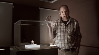 Movie still from “Cave of Forgotten Dreams” (2010), directed by Werner Herzog – A man standing in front of a glass case; Close Up shot, Low angle