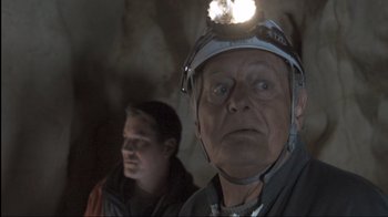 Movie still from “Cave of Forgotten Dreams” (2010), directed by Werner Herzog – A man with a head lamp is in a cave; Close Up shot, Low angle