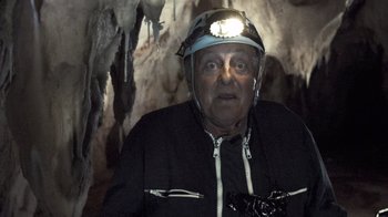 Movie still from “Cave of Forgotten Dreams” (2010), directed by Werner Herzog – An older man wearing a helmet and a jacket; Close Up shot, Low angle