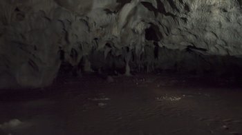 Movie still from “Cave of Forgotten Dreams” (2010), directed by Werner Herzog – A dark cave with a lot of light coming from the ceiling; Extreme Wide shot, High angle