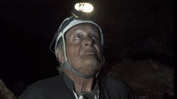 Movie still from “Cave of Forgotten Dreams” (2010), directed by Werner Herzog – An older man wearing a helmet and a light on his head; Close Up shot, Low angle