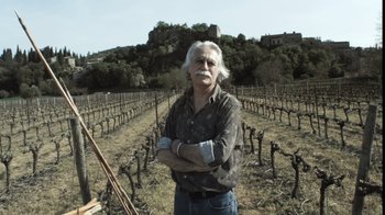 Movie still from “Cave of Forgotten Dreams” (2010), directed by Werner Herzog – An older man standing in front of a field of grapevines; Medium shot, Low angle