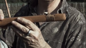 Movie still from “Cave of Forgotten Dreams” (2010), directed by Werner Herzog – A man is holding a wooden stick in his hand; Extreme Close Up shot, Overhead angle