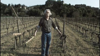 Movie still from “Cave of Forgotten Dreams” (2010), directed by Werner Herzog – An older man in a field holding a stick; Wide shot, Low angle