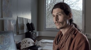 Movie still from “Cave of Forgotten Dreams” (2010), directed by Werner Herzog – A man sitting in front of a window with a helmet; Close Up shot, Over the shoulder angle