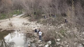 Movie still from “Cave of Forgotten Dreams” (2010), directed by Werner Herzog – A group of people standing next to a river; Extreme Wide shot, High angle