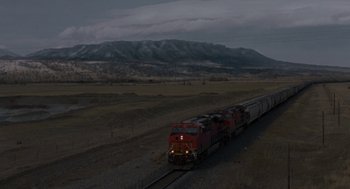 Movie still from “Certain Women” (2016), directed by Kelly Reichardt – A train traveling down train tracks next to a field; Extreme Wide shot, High angle