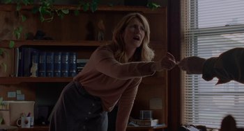 Movie still from “Certain Women” (2016), directed by Kelly Reichardt – A woman in a brown shirt is holding a knife; Medium shot, Over the shoulder angle