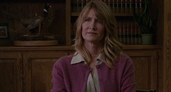 Movie still from “Certain Women” (2016), directed by Kelly Reichardt – A woman wearing a pink sweater sitting in front of a book case; Close Up shot, Over the shoulder angle