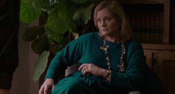 Movie still from “Certain Women” (2016), directed by Kelly Reichardt – A woman sitting in a chair wearing a green dress; Medium shot, High angle