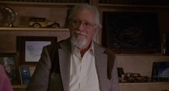 Movie still from “Certain Women” (2016), directed by Kelly Reichardt – An older man wearing a suit and glasses; Close Up shot, Over the shoulder angle