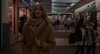 Movie still from “Certain Women” (2016), directed by Kelly Reichardt – A woman wearing a coat and scarf in a mall; Medium shot, Over the shoulder angle